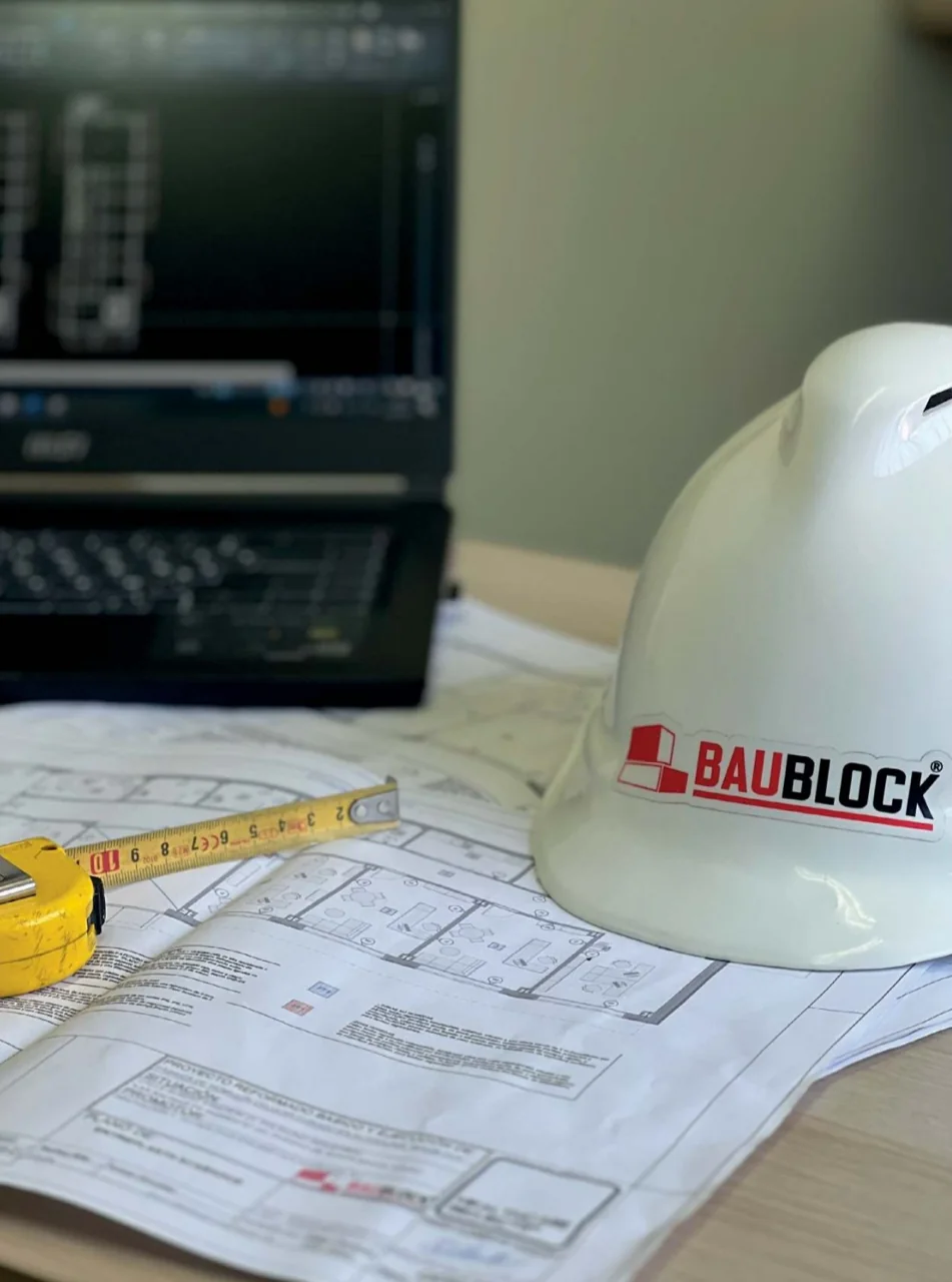 BAUBLOCK hard hat on construction plans with tape measure – planning and technical project support.